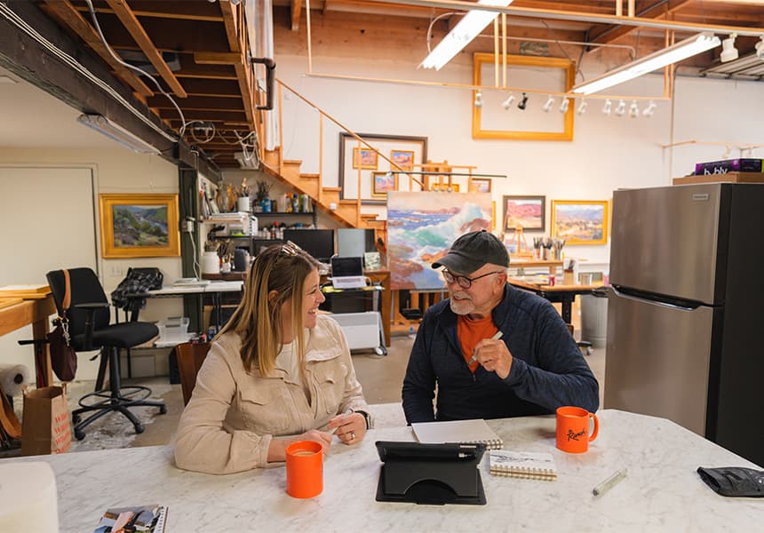 John Cosby chatting in his workspace with a woman over coffee