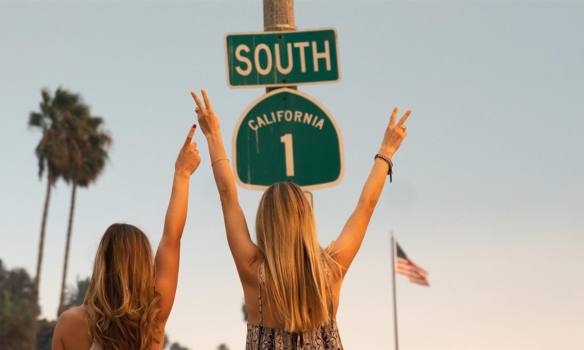women giving peace signs to a California sign