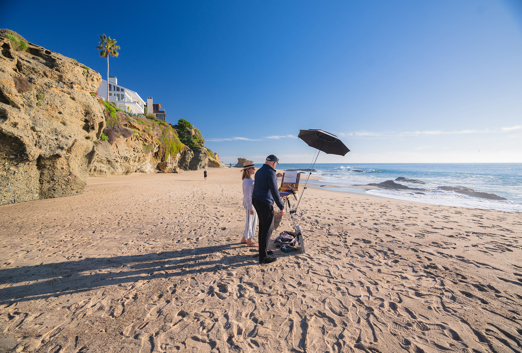 John Cosby instructing a student on the beach with a tall standing easel