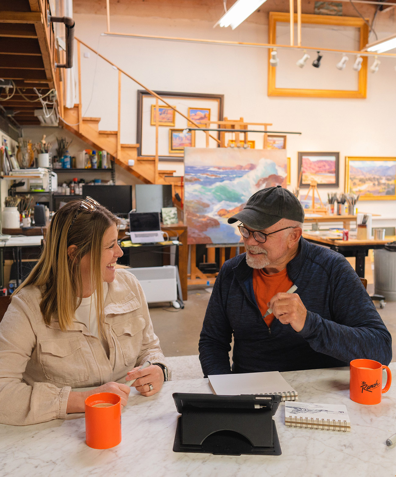 John Cosby chatting in his workspace with a woman over coffee