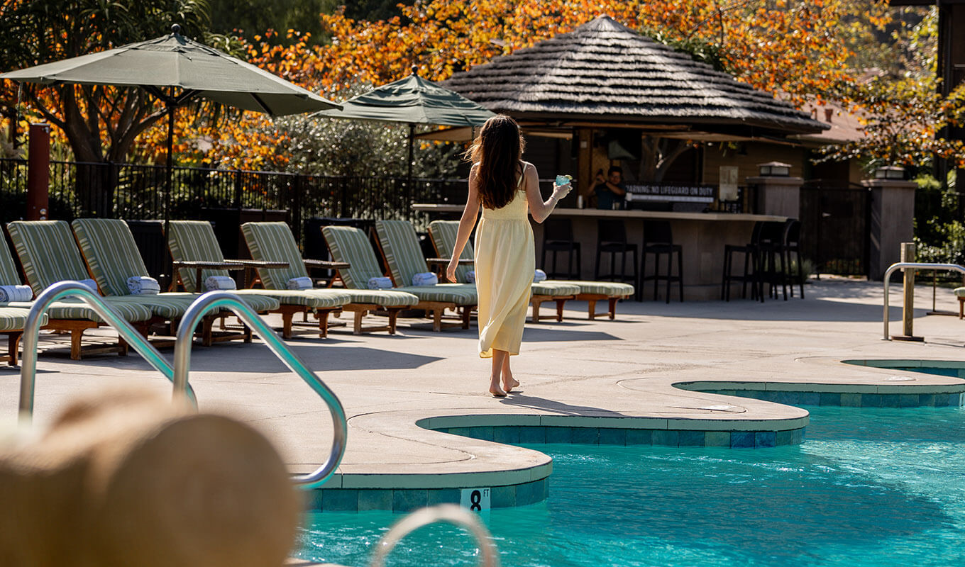 Woman walking by the pool with a drink