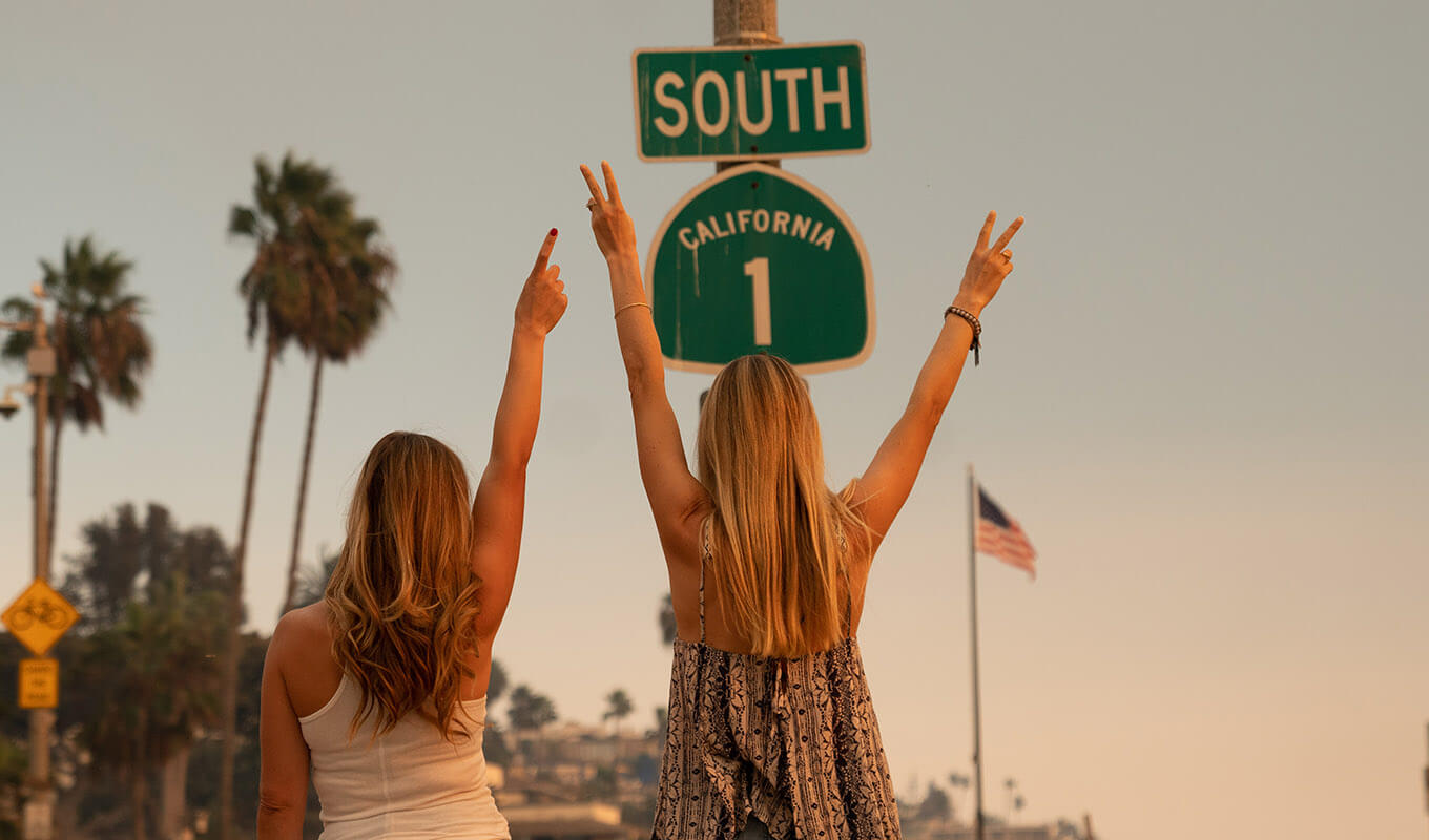 Women by road sign at sunset