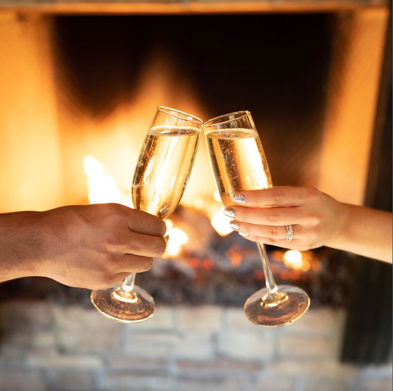 champage toast in front of the fireplace with two guests' hands