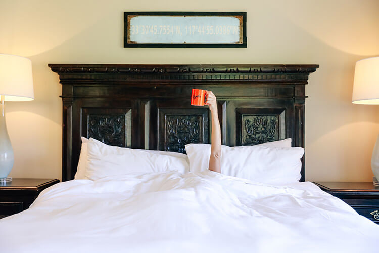 Guest at resort house primary bedroom with orange coffee cup