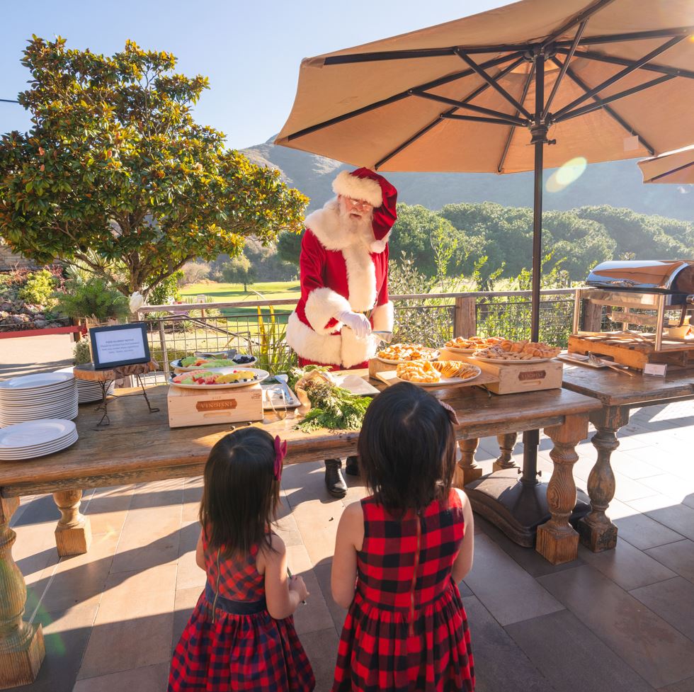 Santa serving breakfast at holiday event with two children
